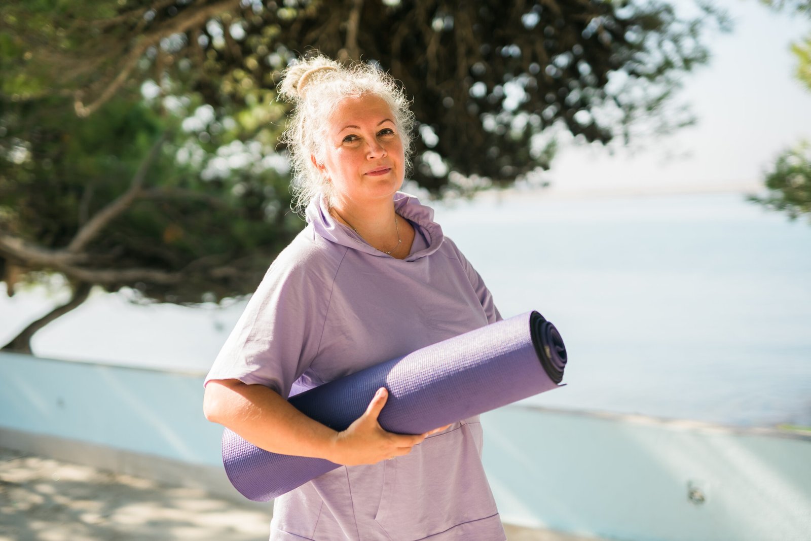 Smiling yoga instructor with a mat, reflecting on how much do yoga instructors make in today’s wellness industry.